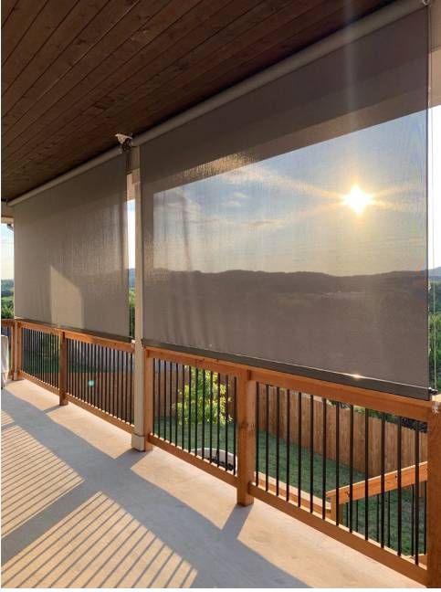 Balcón soleado con barandilla de madera y vistas parciales a las colinas al atardecer.