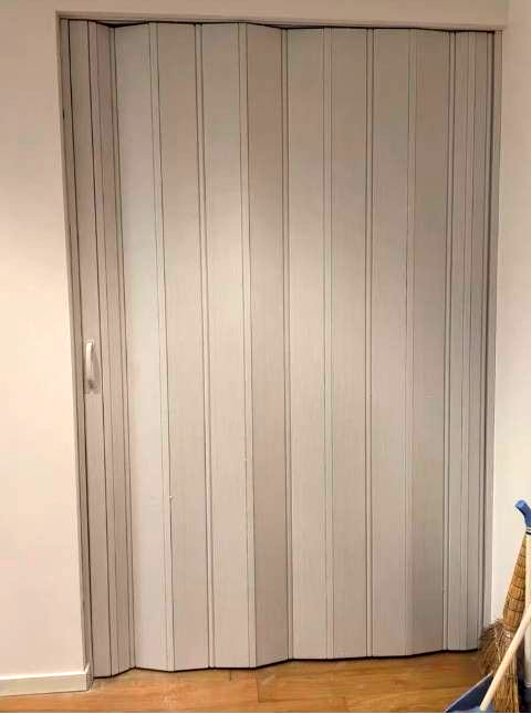 Puertas de armario de madera cerradas en una habitación con suelo de baldosas y luz en el techo.