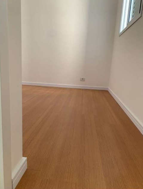 Sala de estar luminosa con suelo de madera, sofá beige, planta en maceta y mesita junto a la ventana.