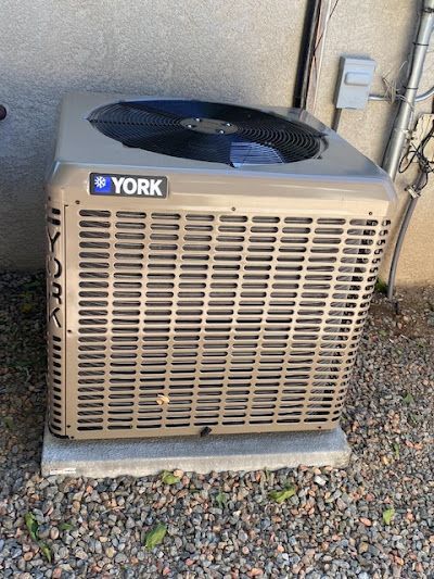 A york air conditioner is sitting on the ground outside of a building.