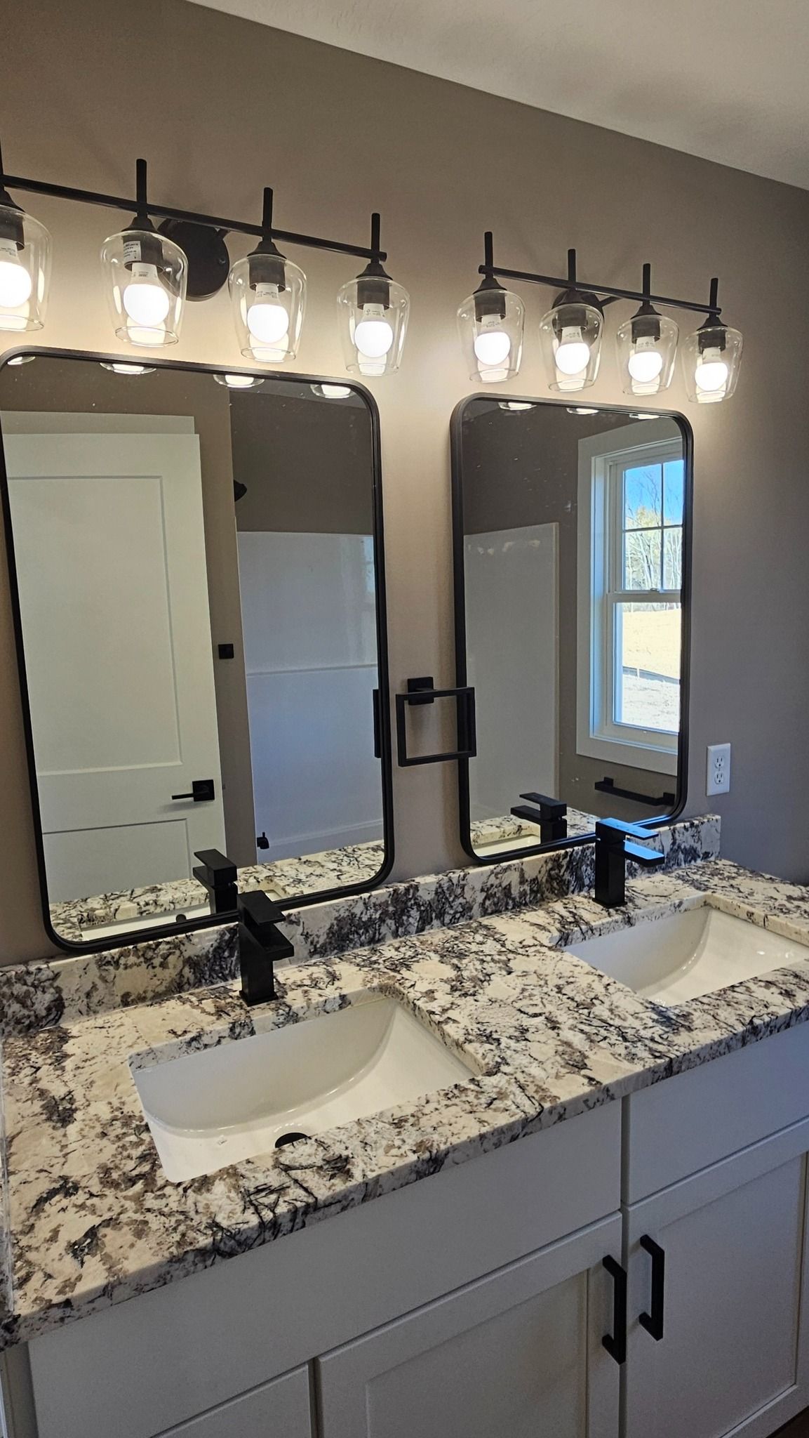 Bathroom with double vanity, two mirrors, and black light fixtures above.