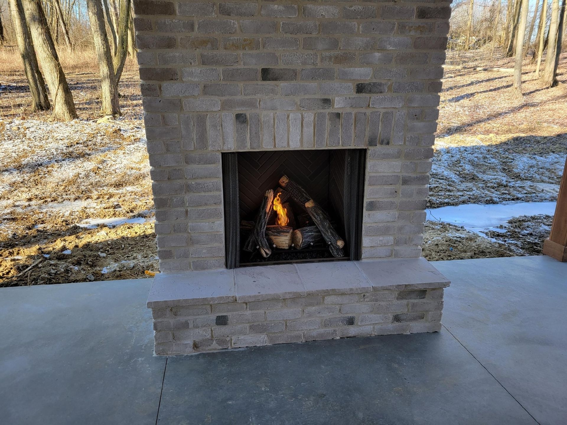 Outdoor stone fireplace with a lit fire.