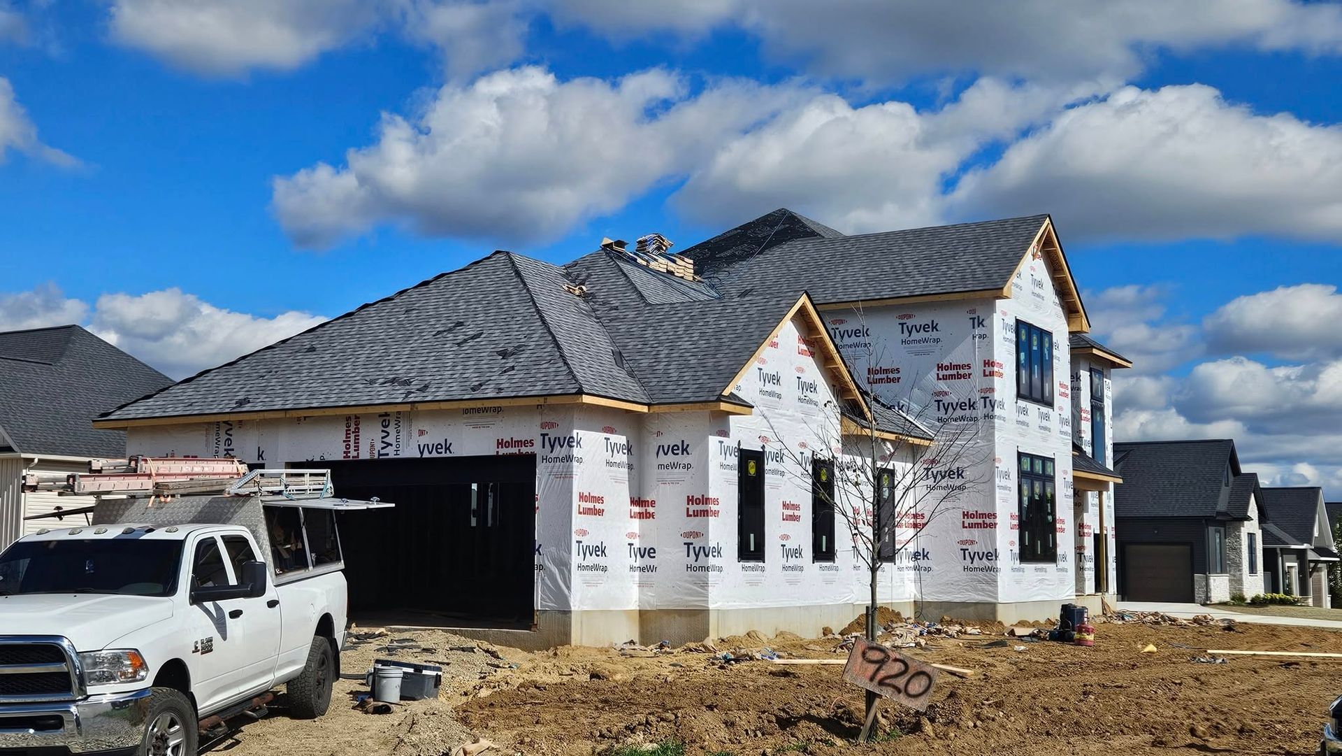 House under construction with grey roof and white truck in front.