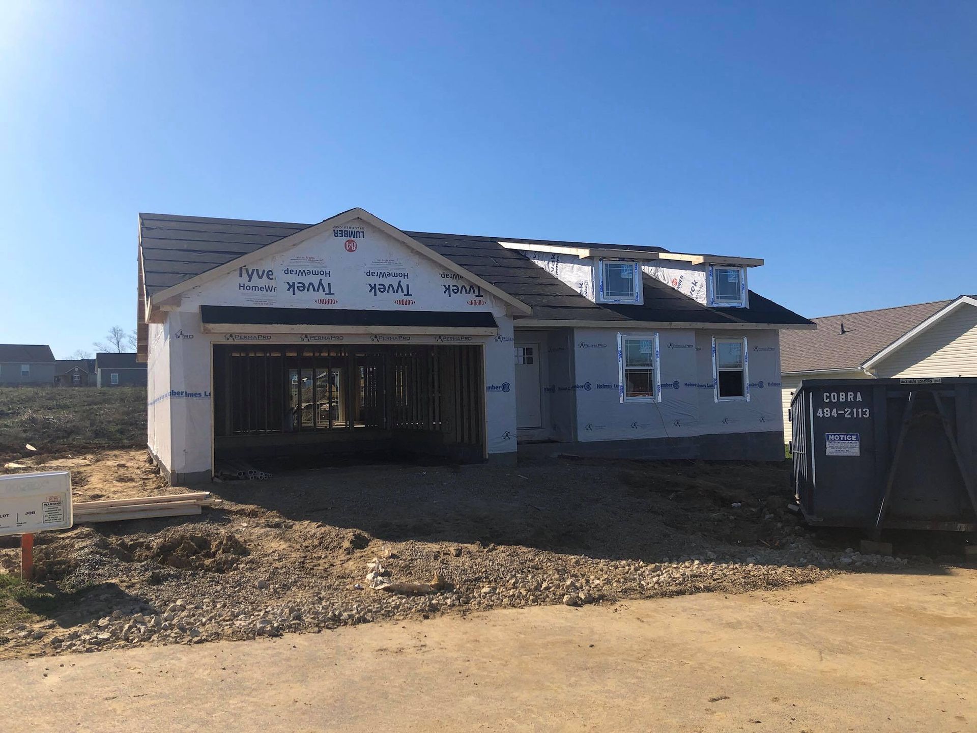 New house under construction with garage and small dormer windows.