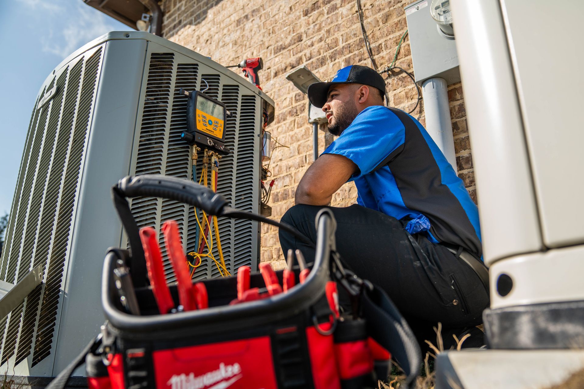 A man is working on a water heater in a garage.