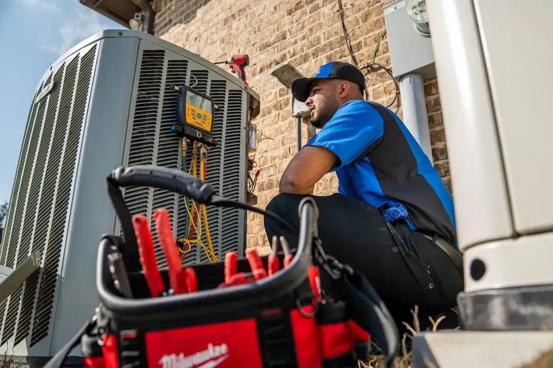 A man is working on a water heater in a garage.