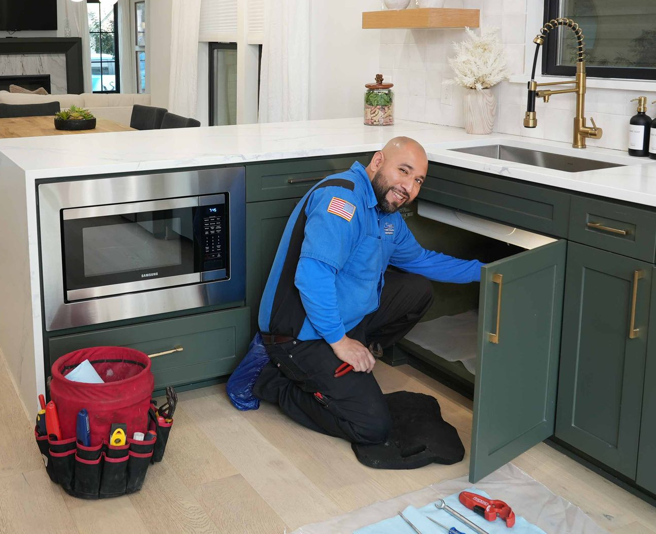 A man in a blue shirt is standing next to a plumbing van