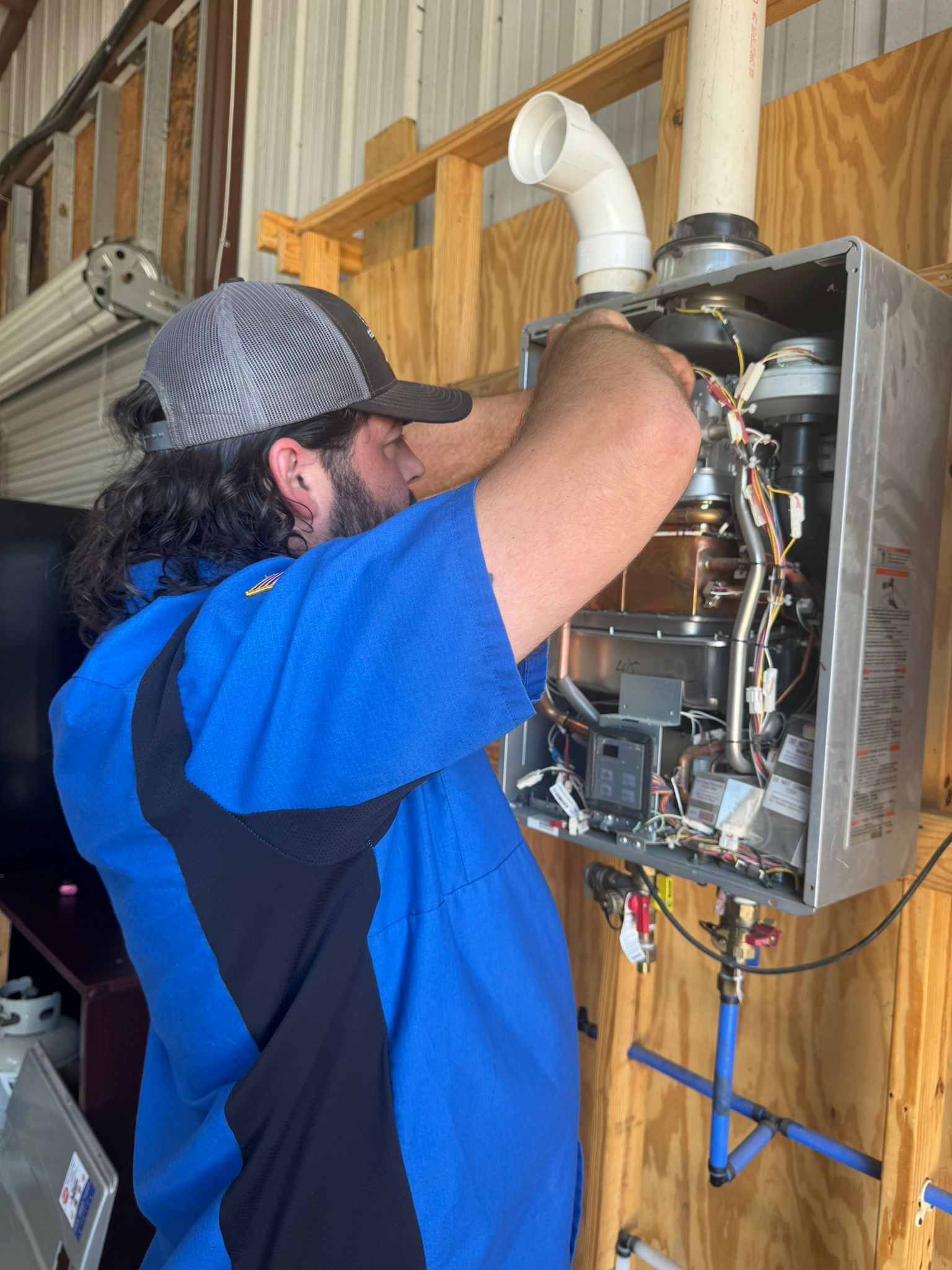 A man is working on a water heater in a garage.