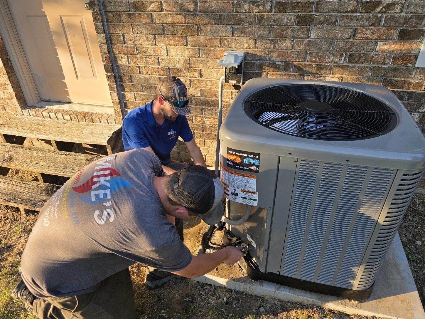 A man is working on an air conditioner outside of a building