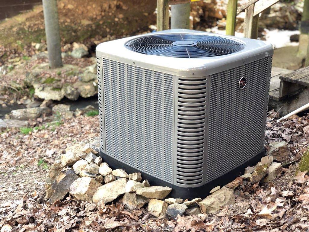 An air conditioner is sitting on top of a pile of rocks.