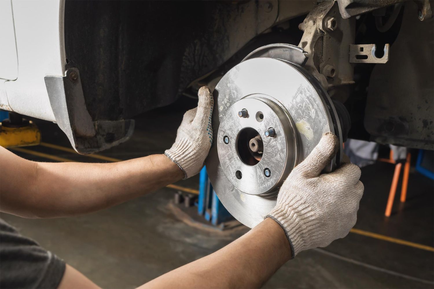 Mechanic installing a brake rotor on a car wheel hub in a garage