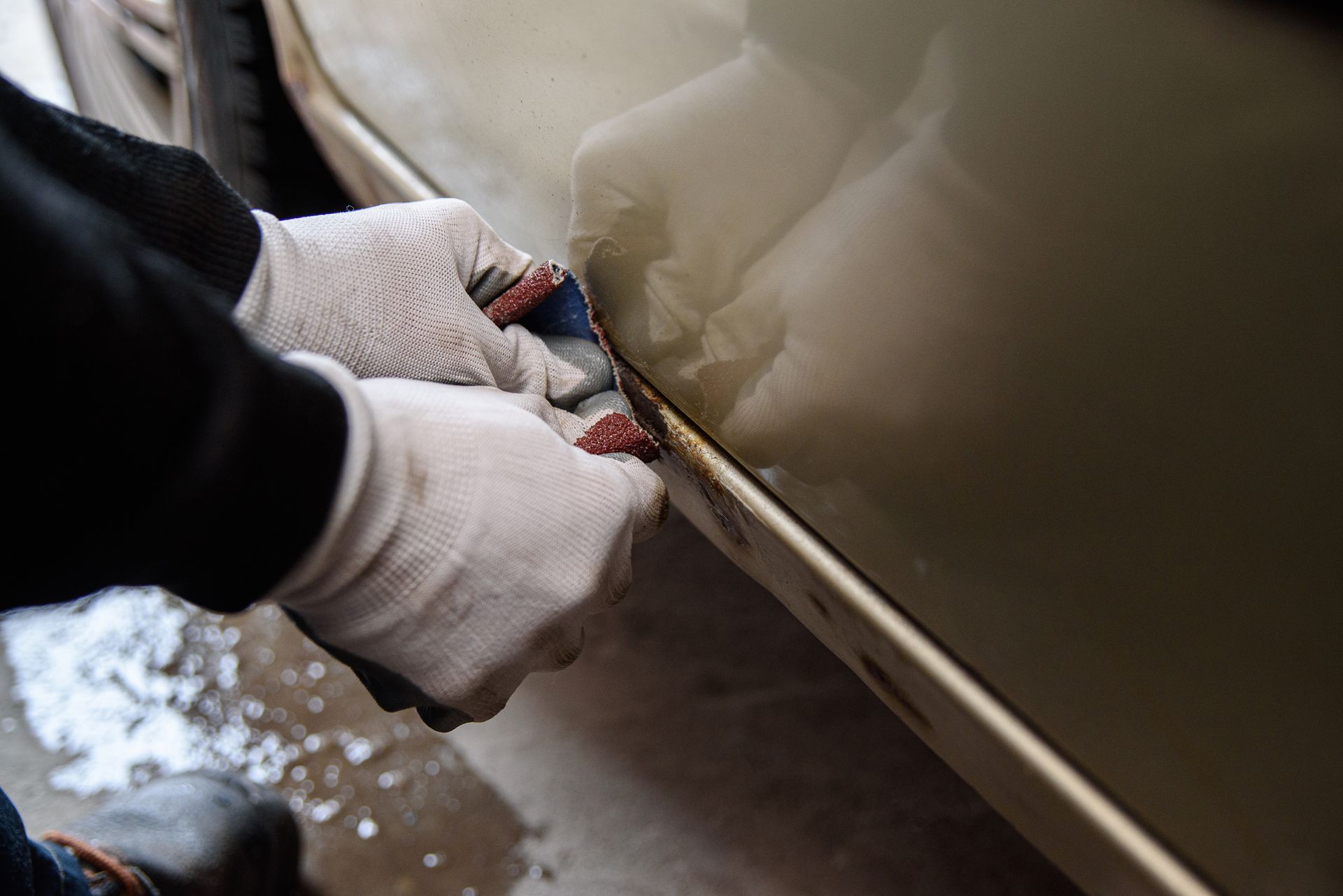 A person is cleaning the side of a car with a cloth.