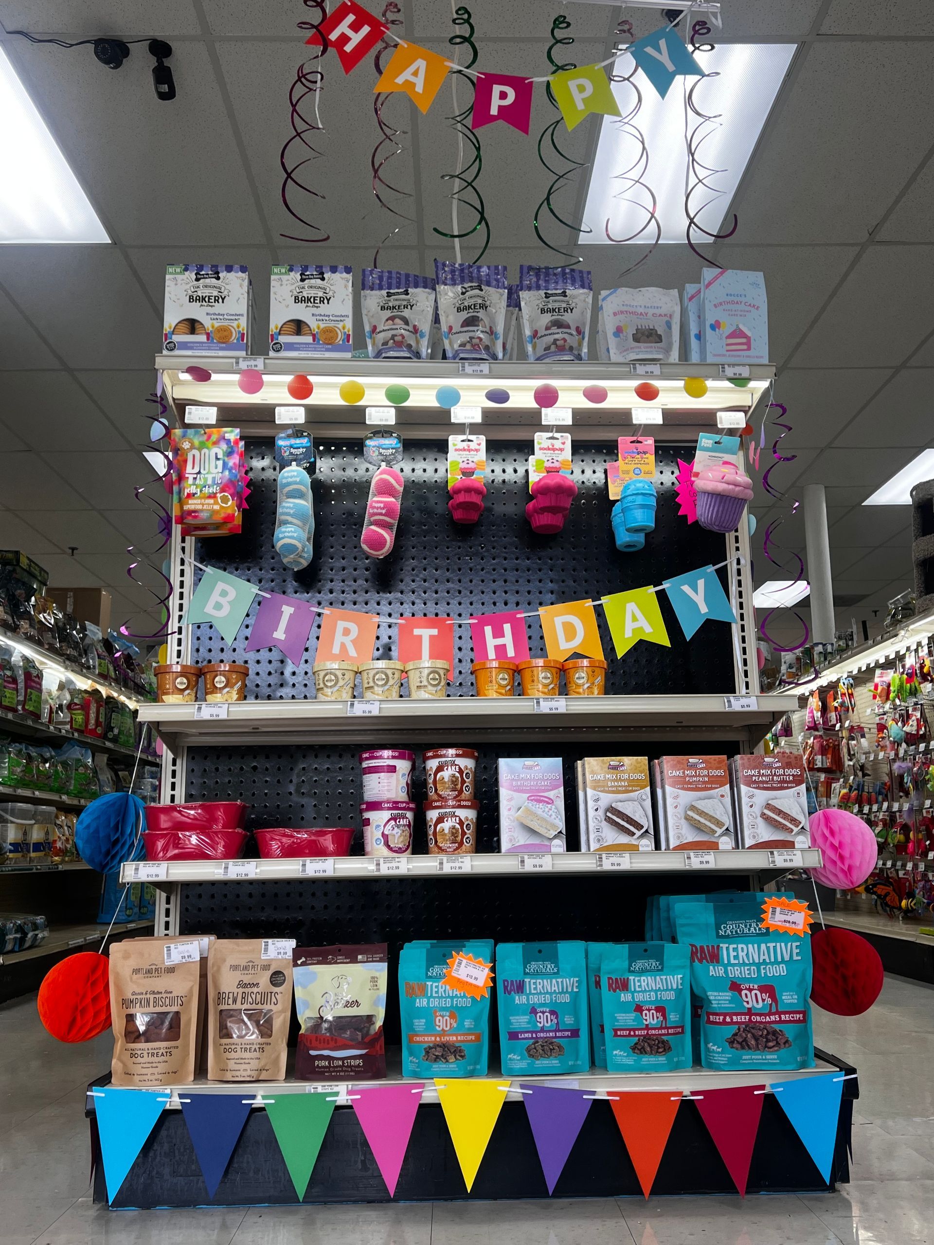 Birthday-themed store display with colorful “Happy Birthday” banners, hanging treats, and party supplies