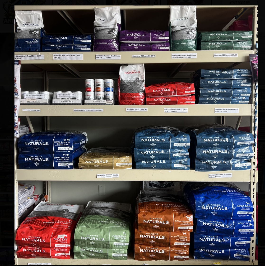 Store shelf stocked with neatly stacked pet food bags in blue, red, green, and brown packages