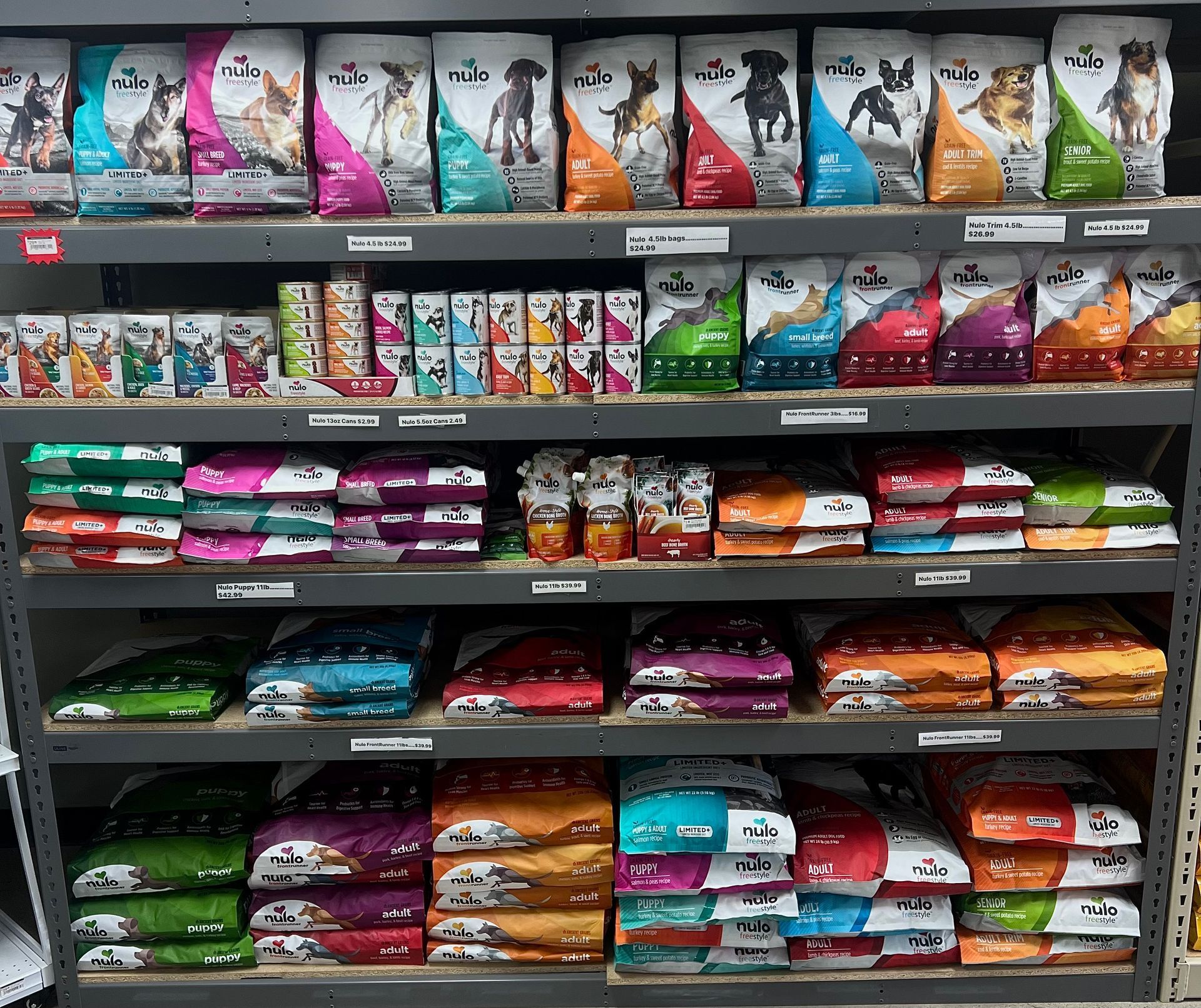 Animal House Pet & Supplies shelf stocked with colorful pet food bags and pouches arranged in rows.