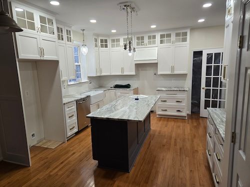 Bright white kitchen with granite island, wood floors, and stainless appliances