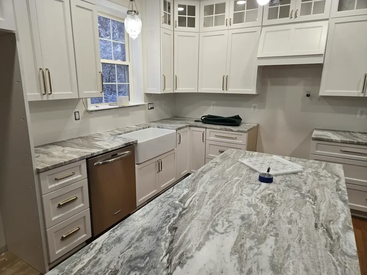 A bright white luxury kitchen with a waterfall edge island and brass hardware in Leonardtown, MD.