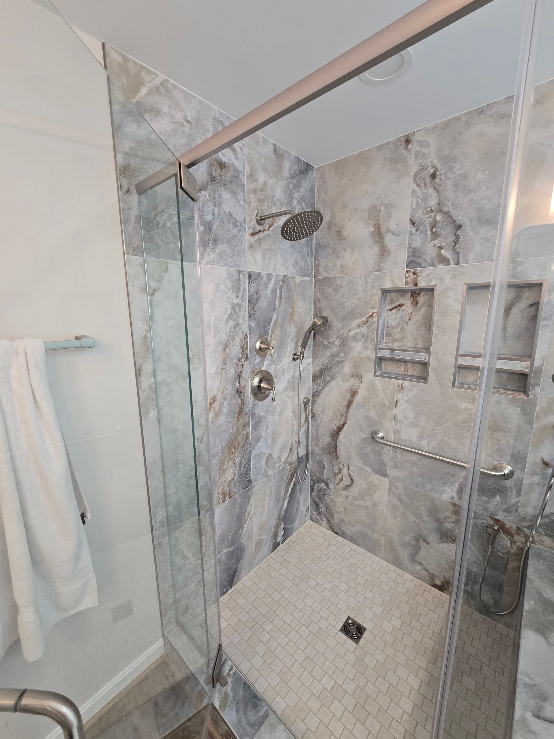Bathroom shower with marble tile walls and glass door.