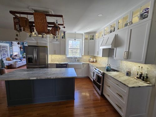 Modern kitchen with island, stainless appliances, white cabinets, and wood floors