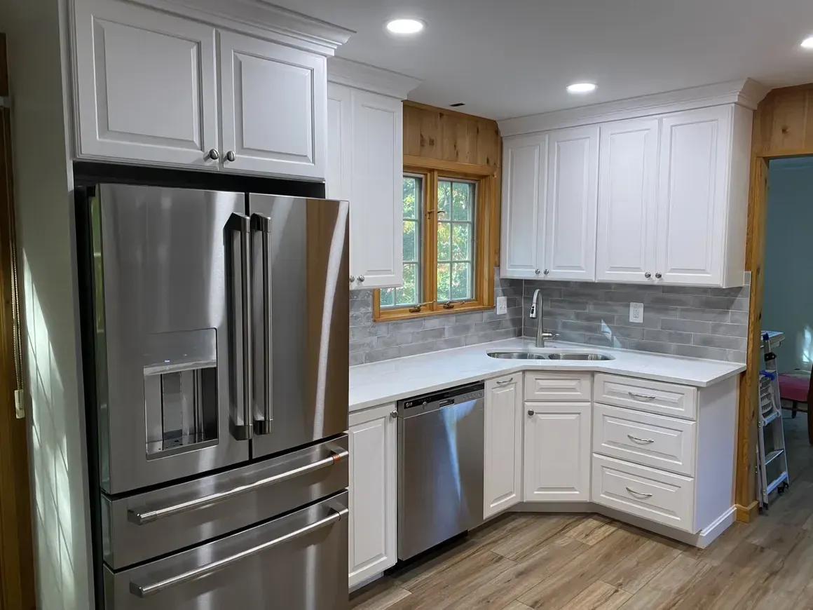 White kitchen cabinets with stainless steel appliances, corner sink, and wooden accents.