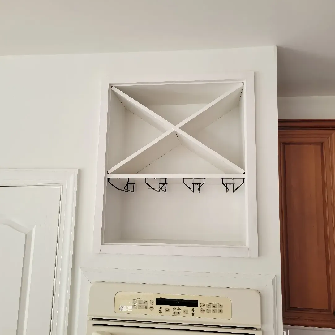 White wine rack built into the wall above an oven, with two glass holders.