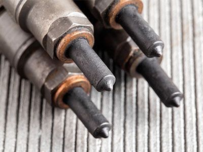 A close up of three injector nozzles on a wooden table - Curry Truck & Auto