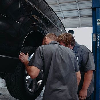 Two men are working on a car in a garage - Curry Truck & Auto
