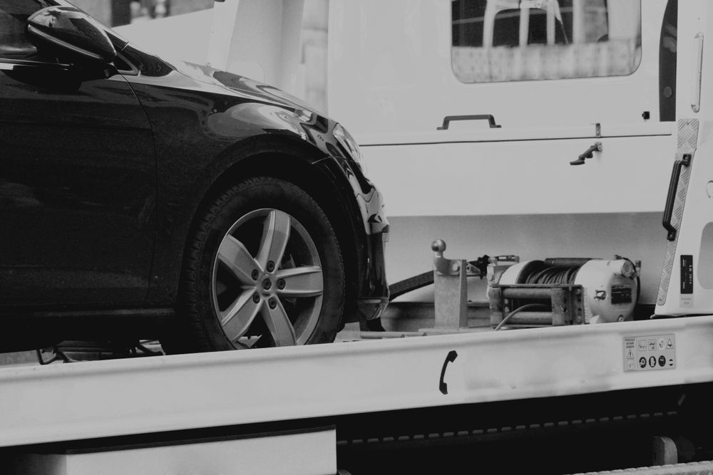 A Black And White Photo Of A Car Being Towed By A Tow Truck — Torquay & Anglesea Accident Towing Centre In Anglesea, VIC