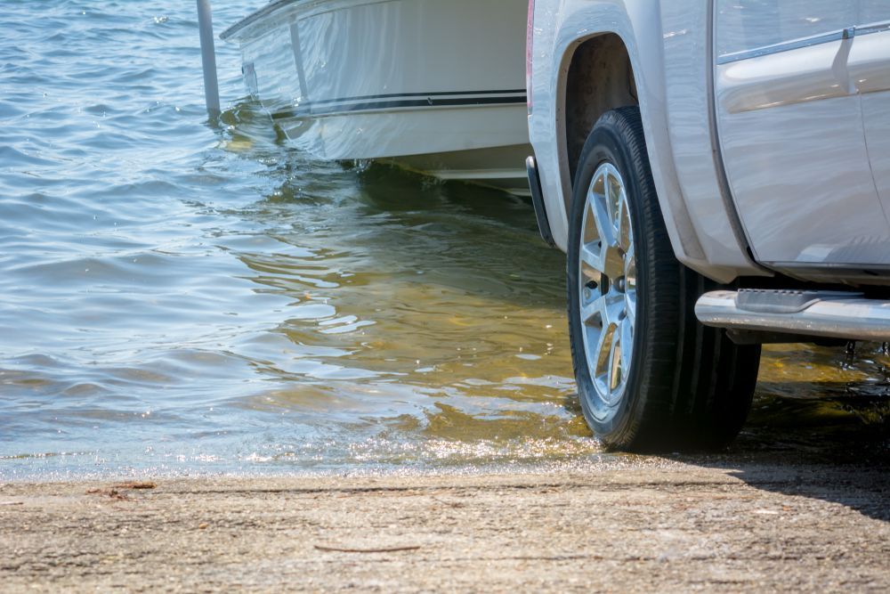 A White Truck Is Parked Next To A Boat In The Water — Torquay & Anglesea Accident Towing Centre In Anglesea, VIC