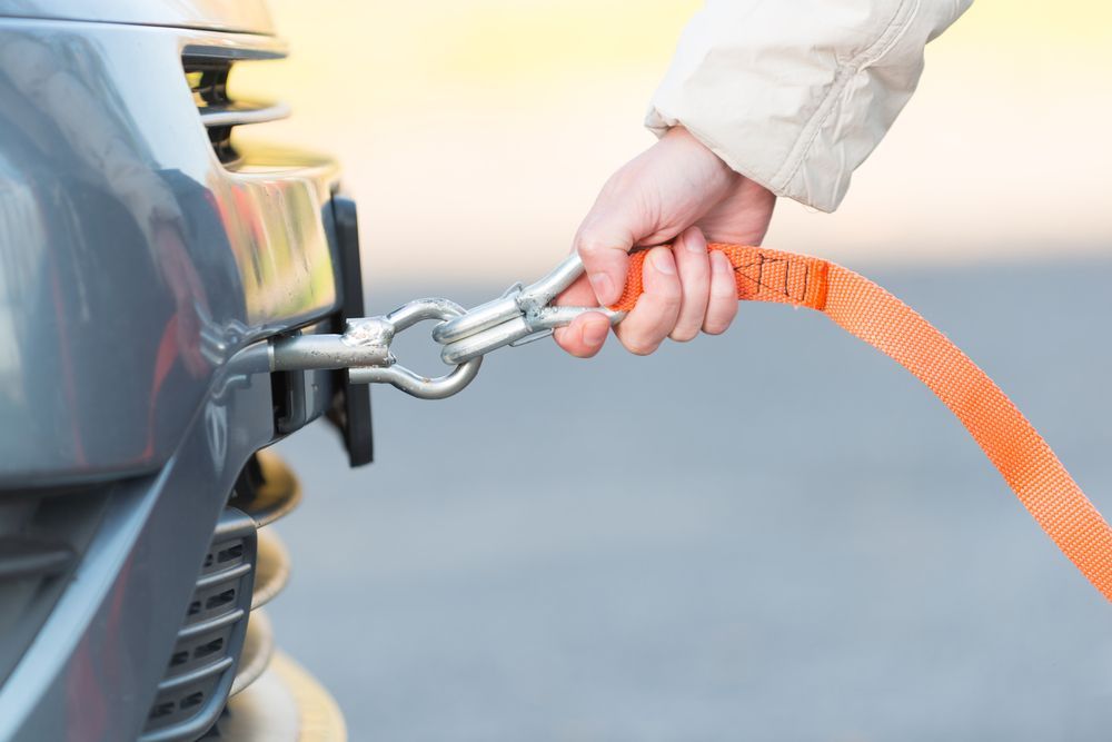 A Person Is Towing A Car With A Tow Strap — Torquay & Anglesea Accident Towing Centre In Winchelsea, VIC