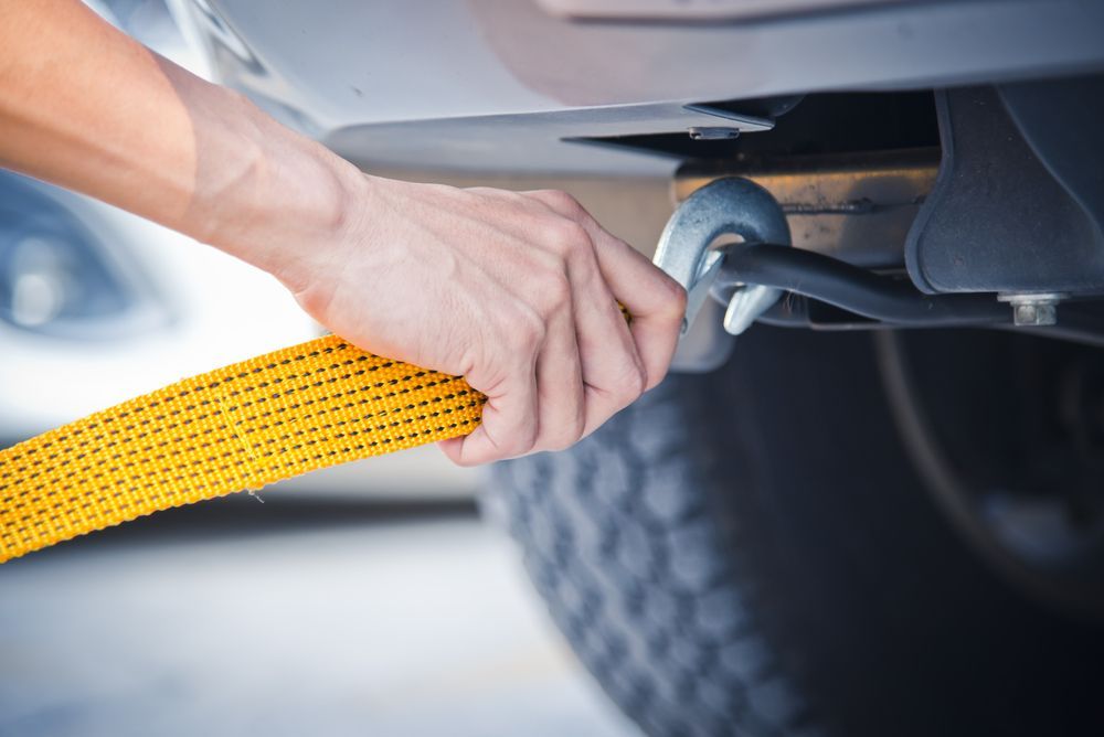 A Person Is Towing A Car With A Yellow Tow Strap — Torquay & Anglesea Accident Towing Centre In Aireys Inlet, VIC