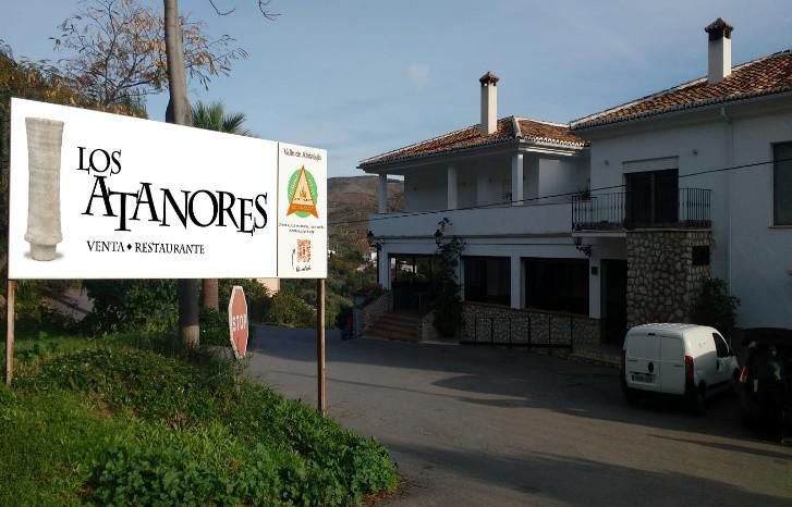 A white van is parked in front of a building with a sign that says los atanores