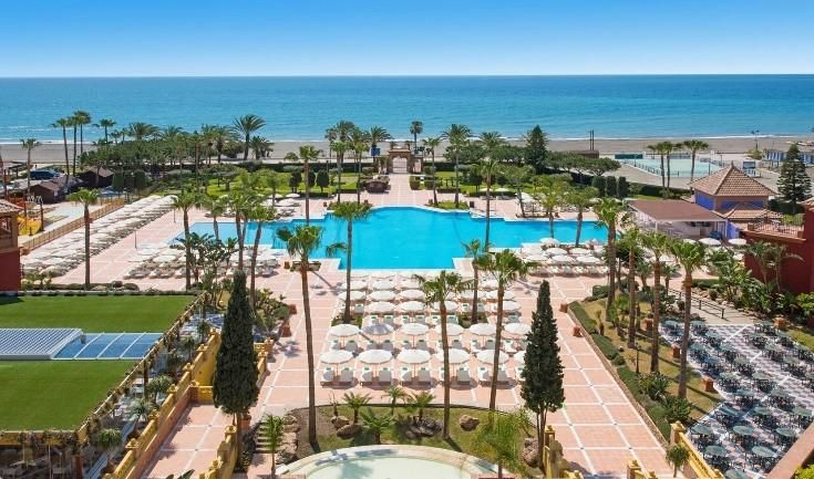 An aerial view of a resort with a large pool and palm trees