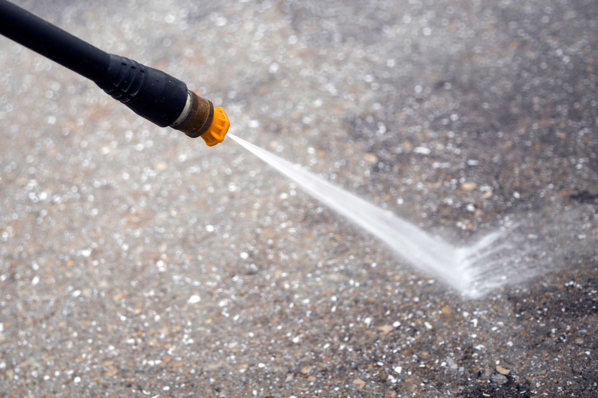 Garden hose spraying water onto a paved surface