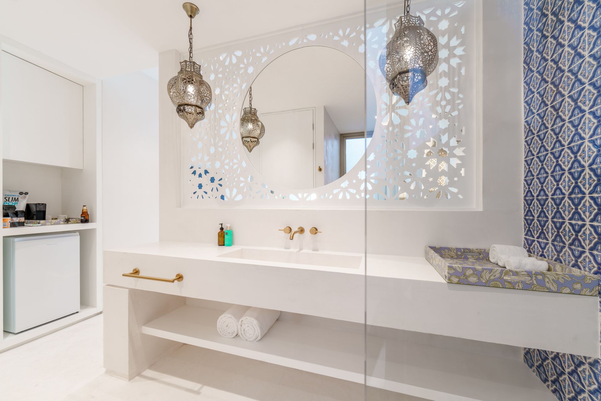 White bathroom with ornate mirror, decorative hanging lights, and blue patterned wall.