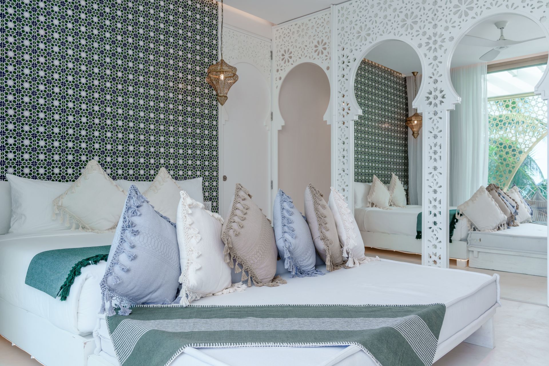 Dormitorio con cama blanca, cabecero estampado en verde y arcos decorativos.