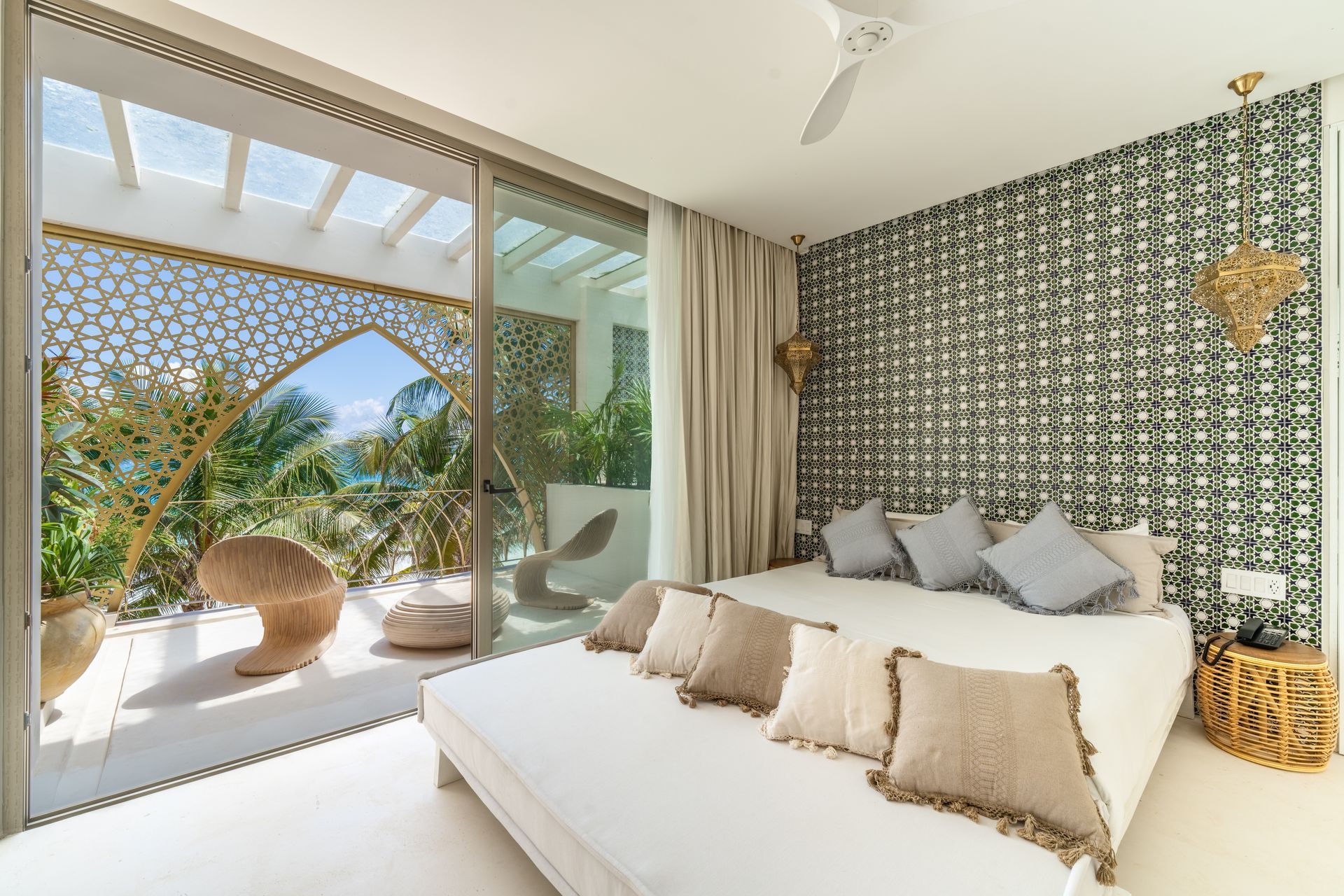 Dormitorio con cama grande, papel pintado estampado y balcón con vista al mar.