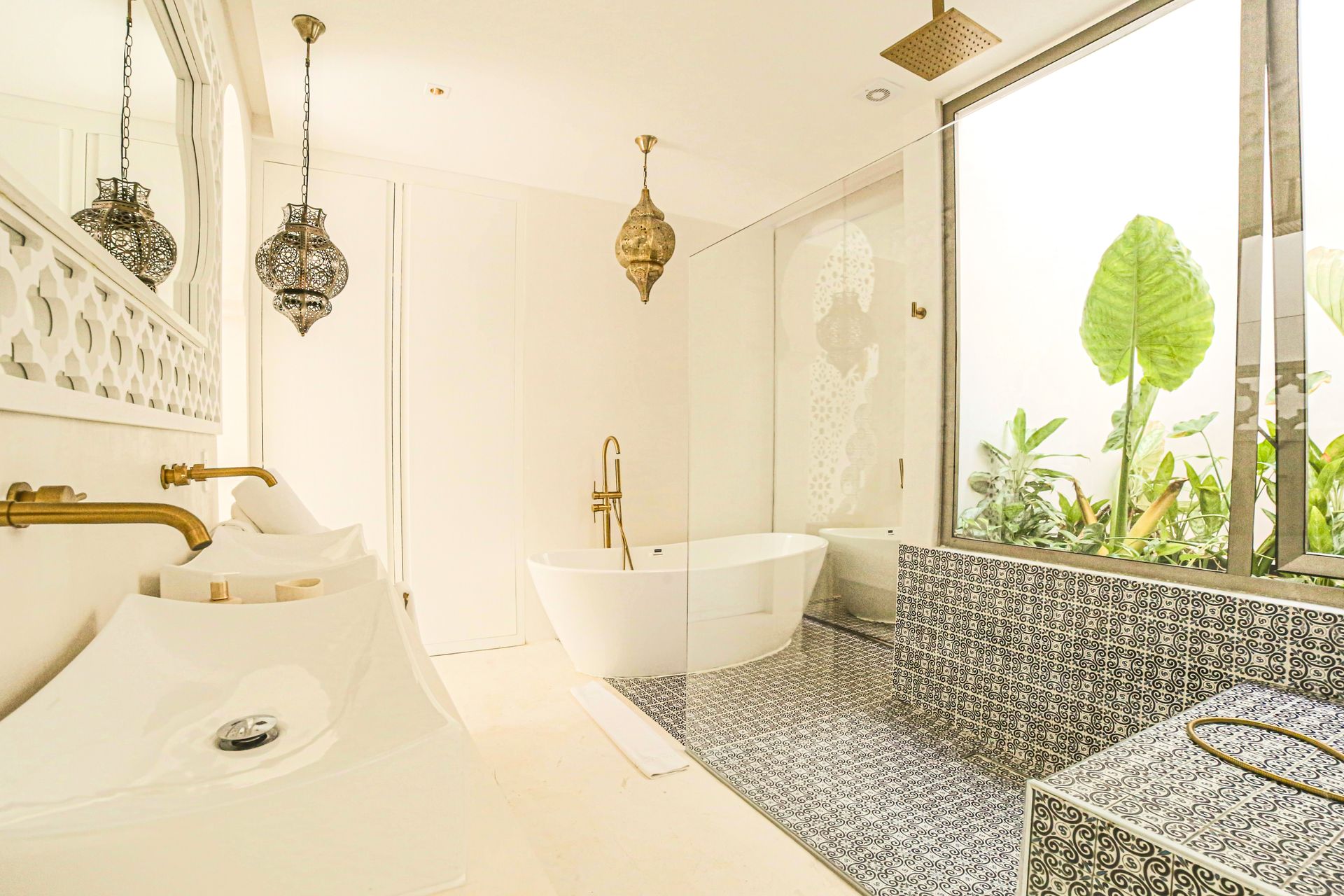 Lujoso baño blanco con bañera independiente, accesorios dorados y piso de mosaico.