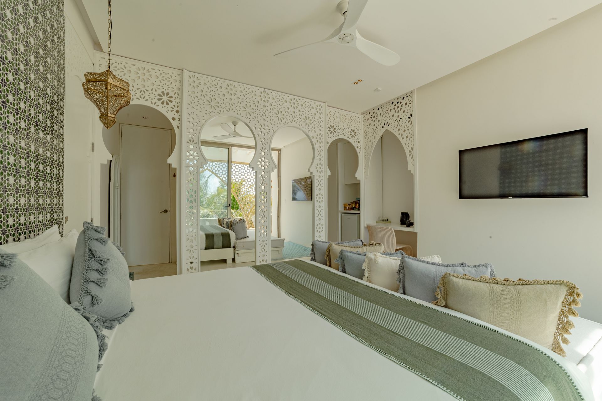 Bedroom with ornate white archway, TV, large bed with pillows, and decorative gold lantern.