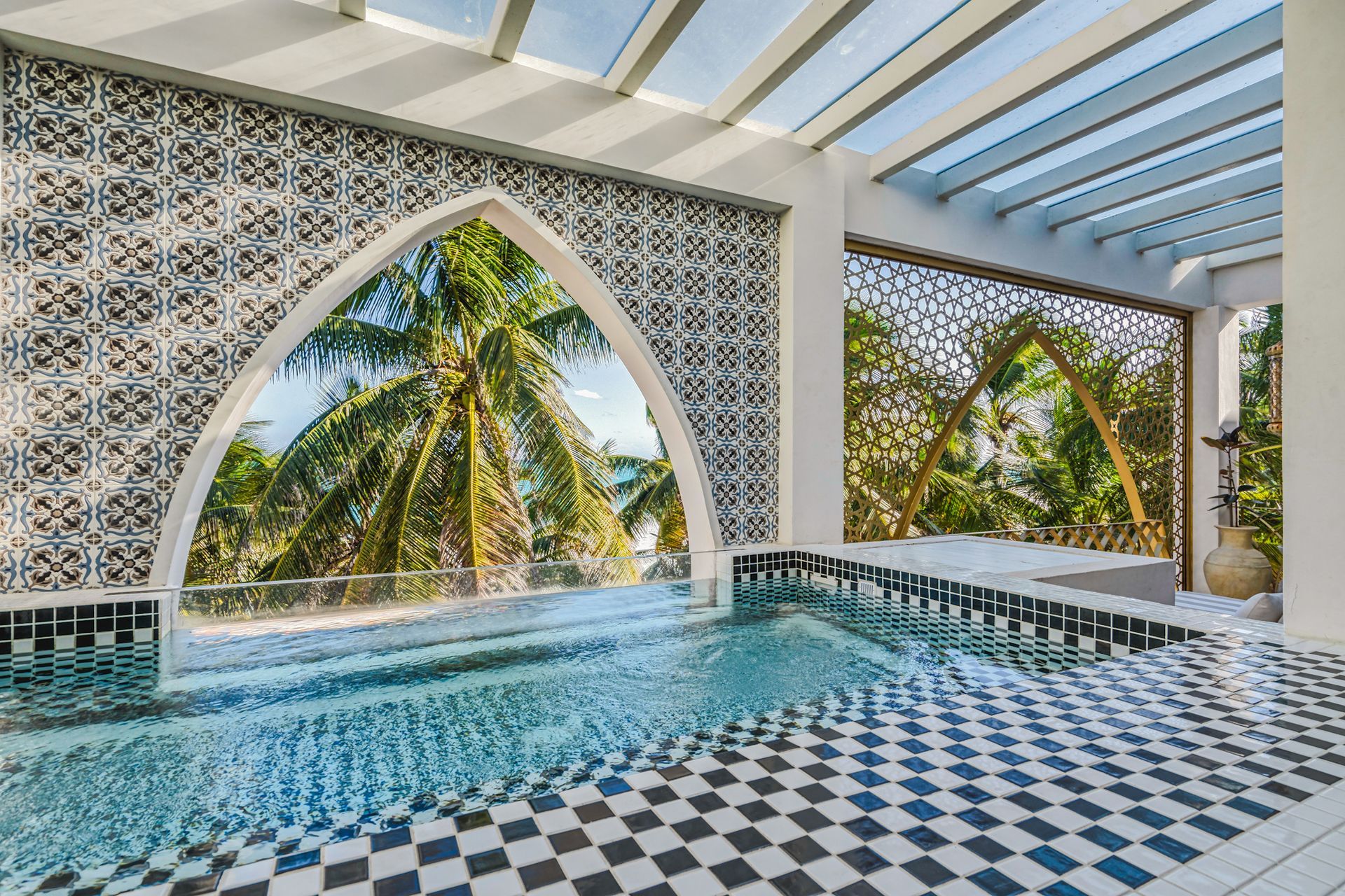 Piscina con azulejos estampados y vista en arco a las palmeras.