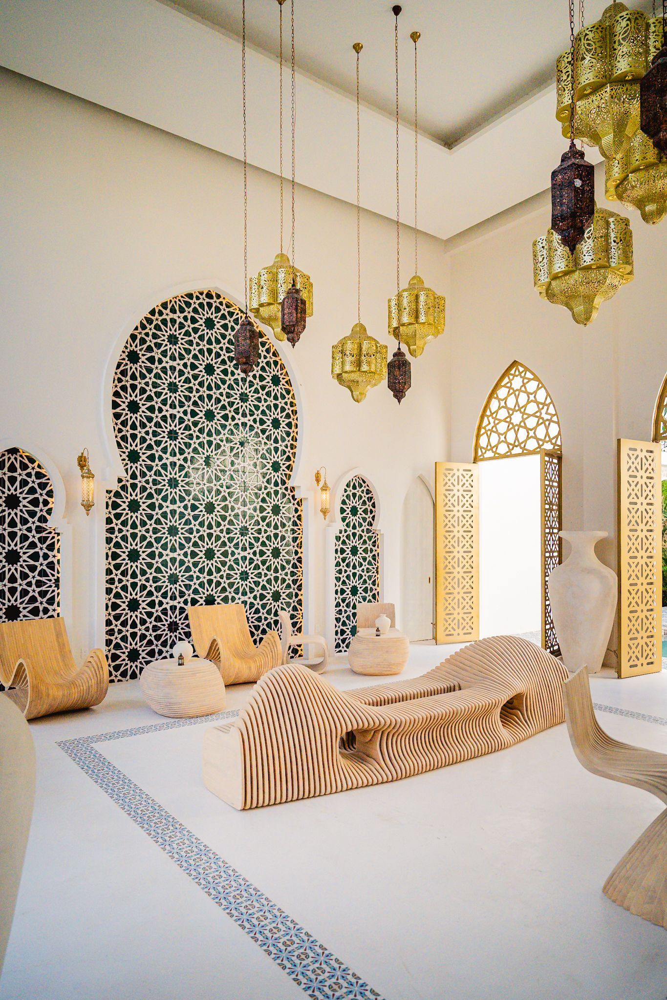 Habitación de estilo marroquí: puertas arqueadas, paredes de azulejos estampados, faroles ornamentados, asientos tipo lounge y decoración geométrica.