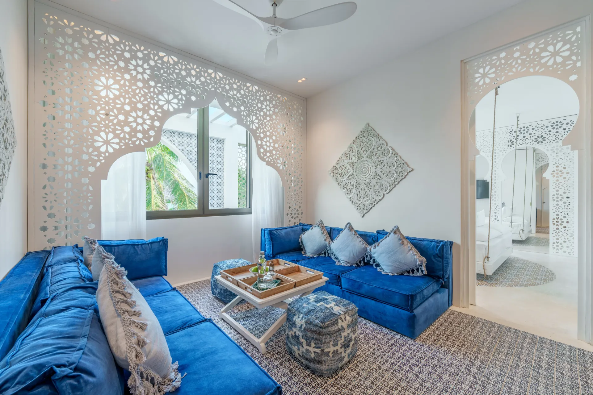 Sofás azules en una habitación blanca con un diseño recortado ornamentado y una ventana.