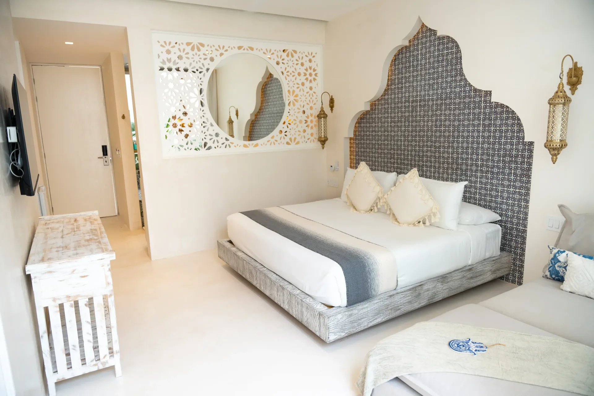 Dormitorio blanco luminoso con cama, cabecero y detalles decorativos.