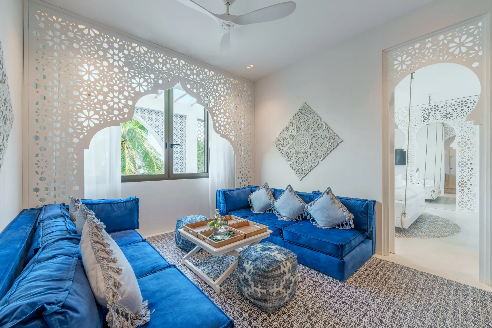 Sofás azules en una habitación blanca con una decoración de pared recortada y una alfombra estampada.