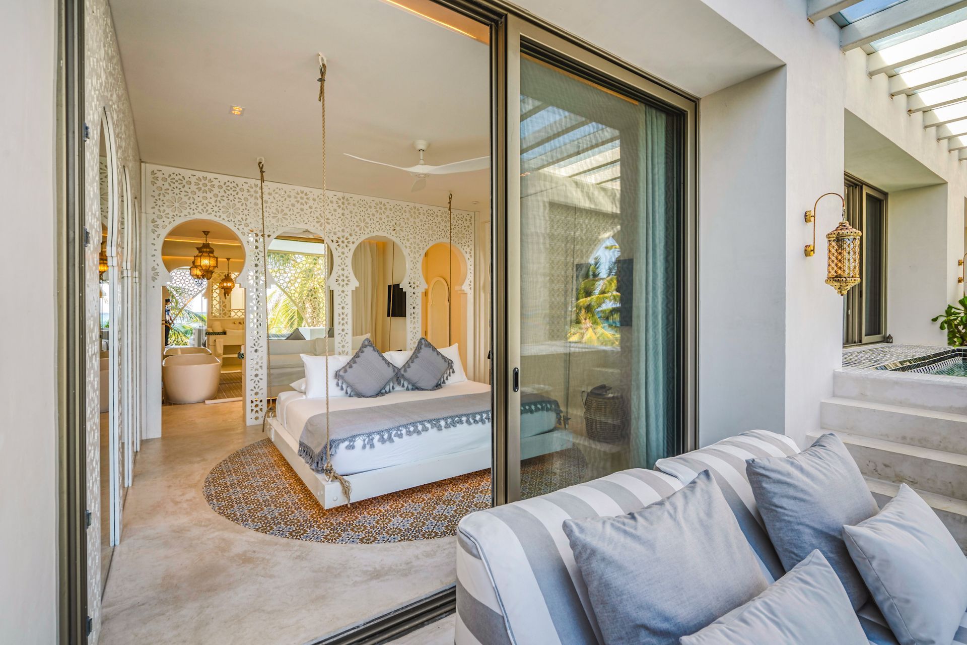 Bedroom with bed, open door to patio with sofa, ornate arched details.