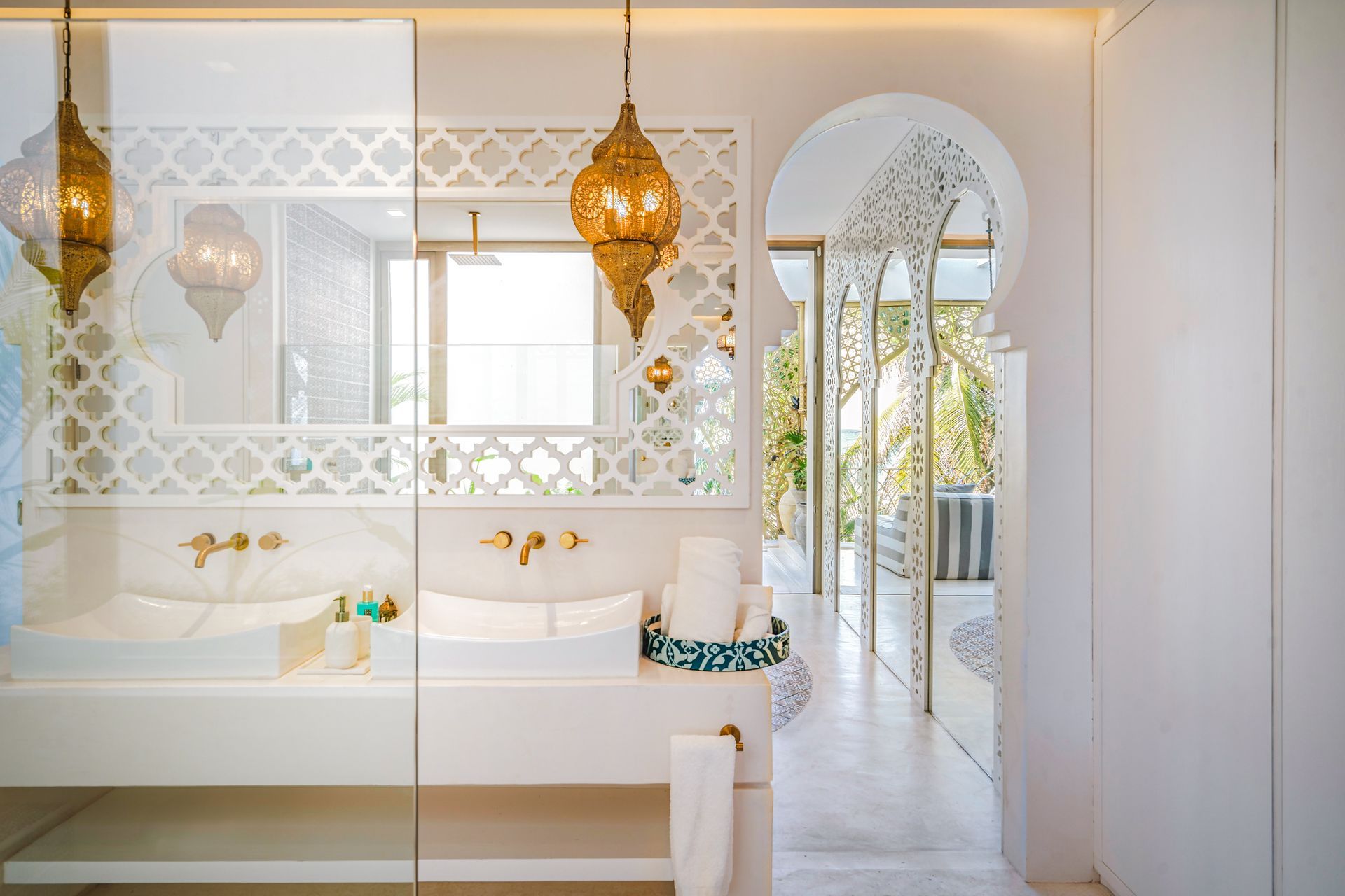 Bathroom with ornate gold lanterns, white decor, and an arched doorway leading to an outdoor seating area.