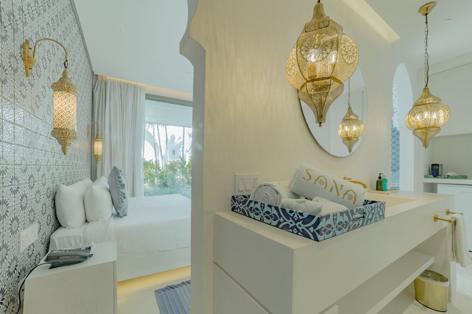 Dormitorio y baño de estilo lujoso, paredes blancas, faroles dorados colgantes, detalles azules, cama visible.