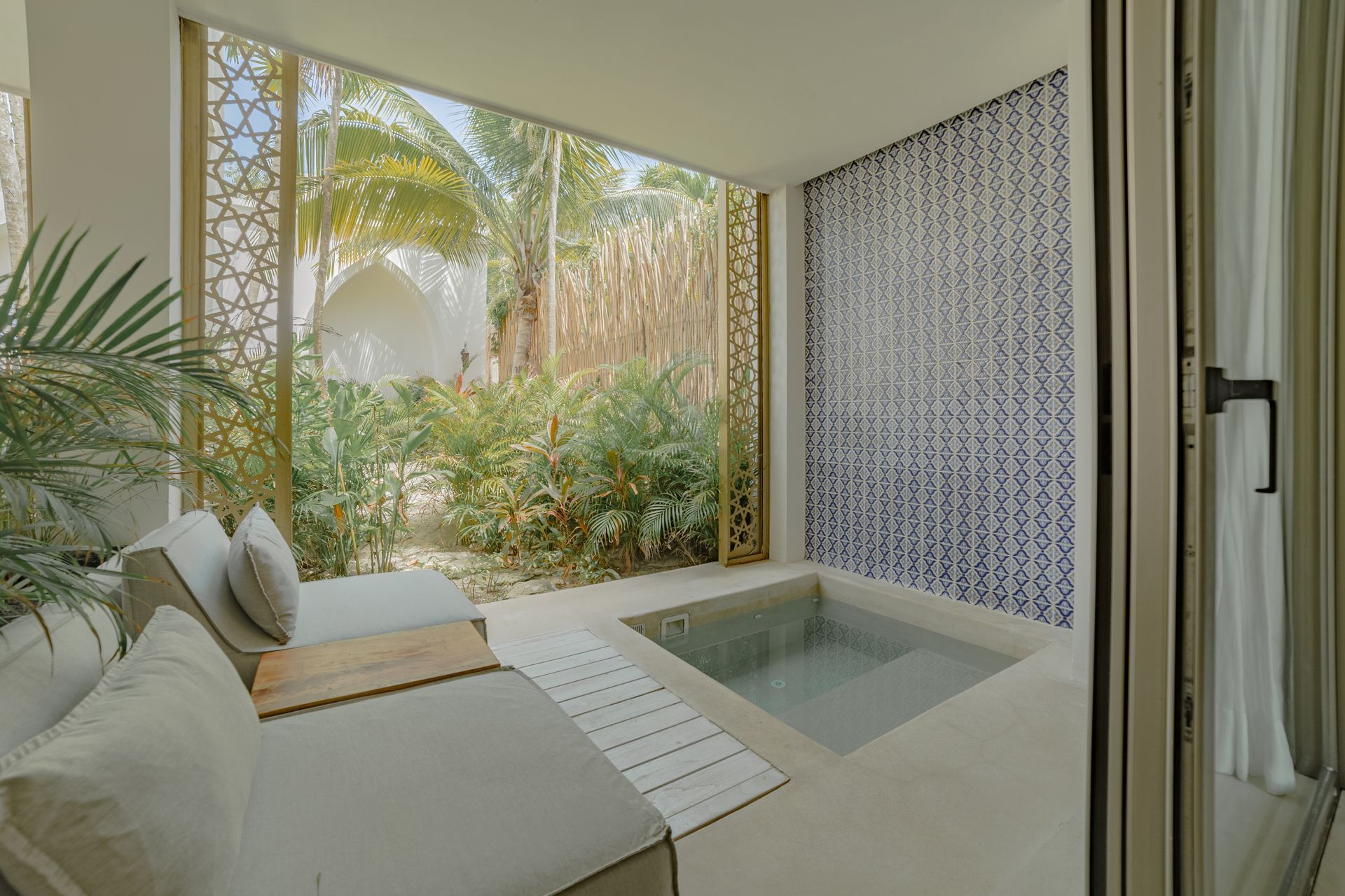 Un patio privado con dos tumbonas, una pequeña piscina y una pared decorativa.