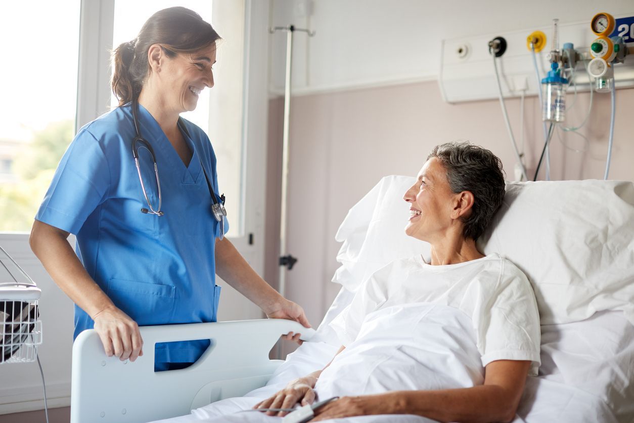hospital sitter or nurse talks with female patient in hospital bed