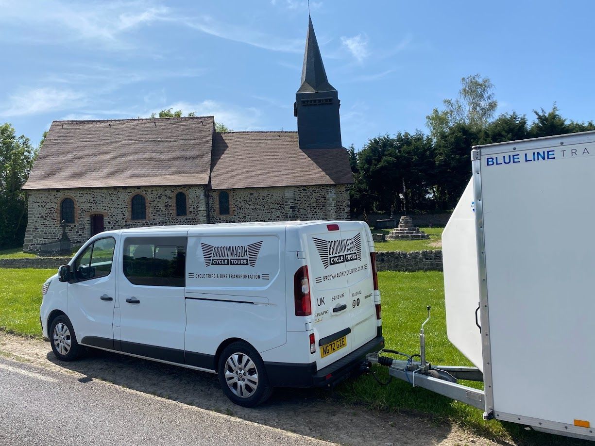 White van with black wheels parked outdoors, labeled “BROOMWAGON CYCLE TOURS” on the side.